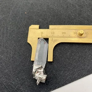 Detailed measurement of white crystal pendant width using brass calipers on black background