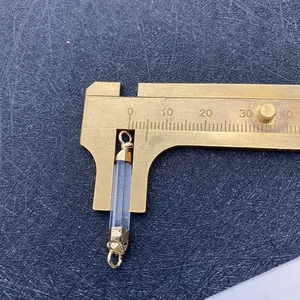 Detailed view of clear natural quartz cylinder pendant with gold caps measured by caliper