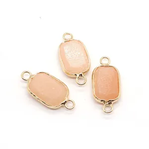 Close-up of rectangular light pink stone connectors with gold edges and double bail loops