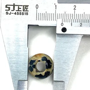 Makro-Detail einer 14,5 mm Dalmatiner-Jaspis-Perle, die mit einem Messschieber gemessen wird