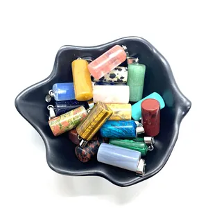 Macro shot of assorted cylindrical gemstone pendants with silver hooks in a black bowl