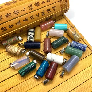 Macro view of assorted cylindrical gemstone pendants with silver metal bails on bamboo mat