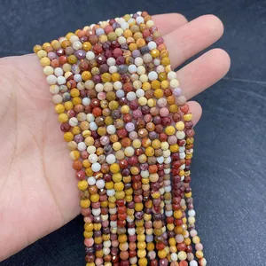 Detailed view of 2-3mm faceted multi-color natural gemstone beads held in hand for scale
