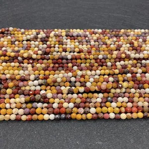 Macro detail of faceted 3-4mm mookaite jasper beads on a dark slate background
