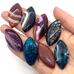 Eight colorful marquise-shaped dragon vein agate stones held for size display