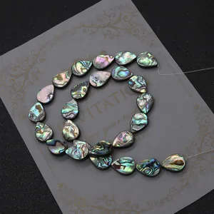Schillernde Abalone-Muschelperlen in Tropfenform für DIY-Schmuck auf Texturhintergrund