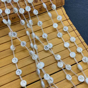 Detailed macro view of 8mm white shell-textured beads with golden alphabet letters for DIY