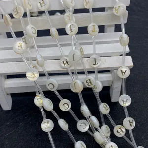 Macro shot of 8mm white shell round beads with gold alphabet engraving for DIY jewelry