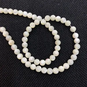 Dettaglio macro di perle di conchiglia naturale con riflessi iridescenti su tessuto