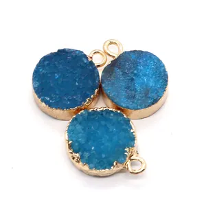 Détail macro de trois breloques circulaires en druzy bleu avec bordure en métal doré