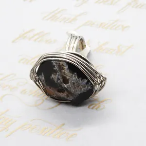 Detailed wire-wrapped silver finish on a natural black agate stone ring with raw textures