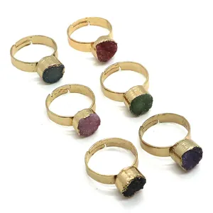 Detail of six adjustable gold-plated rings featuring colorful round druzy crystal stones