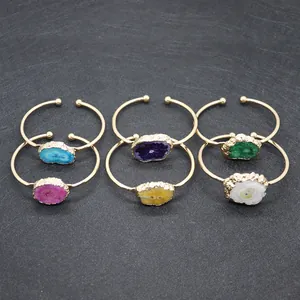 Dettaglio di sei bracciali dorati regolabili con pietre di agata druzy grezze colorate