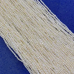 Vista macro di perle d'acqua dolce a chicco di riso da 2mm bianco crema su sfondo blu