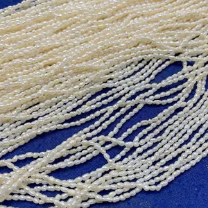 Fili di perle naturali d'acqua dolce a forma di riso su uno sfondo di tessuto blu scuro