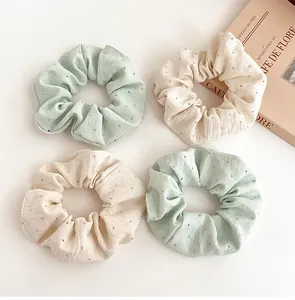 Close-up of four rhinestone scrunchies in mint green and beige with cloth textures