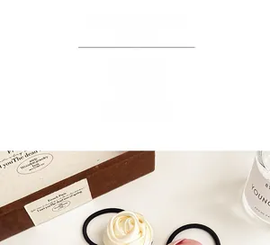 Detailed view of handmade satin rose hair ties in beige and pink on a wooden box