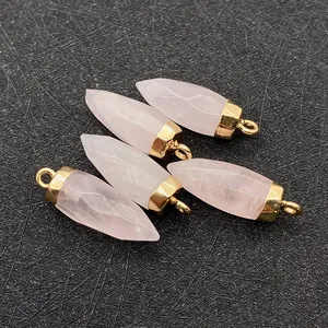 Macro-opname van vijf gefacetteerde rozenkwarts hangers met goudkleurige metalen oogjes
