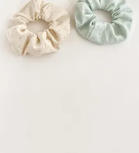 Close-up of beige and mint green textured scrunchies with elegant rhinestone details