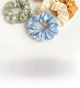 Detailed texture of fabric floral scrunchies in green, yellow, blue, and orange colors
