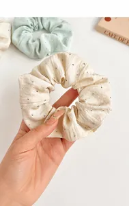 Close-up of fabric scrunchies with silver rhinestones in mint green and beige colors