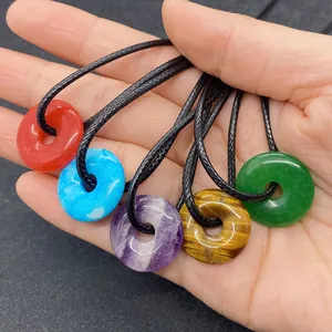 Close-up of five natural stone donut pendants in agate, turquoise, amethyst, and jade