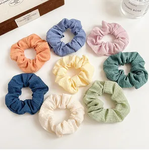 Flat lay of eight colorful elastic hair scrunchies in various pastel and deep tones
