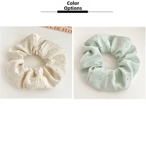 Close-up of beige and green pleated scrunchies with elegant rhinestone accents