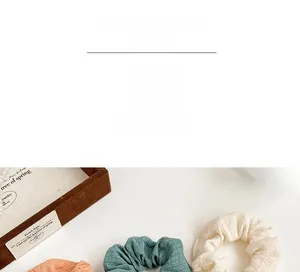 Detailed texture of pleated fabric hair scrunchies in peach, teal and cream white