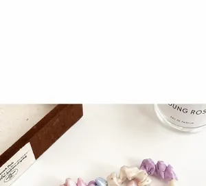 Gros plan de chouchous en satin pastel avec strass et plis doux sur surface neutre