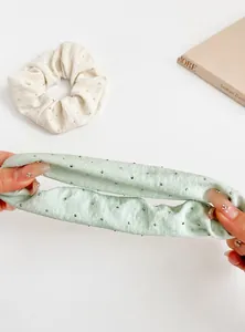 Detailed view of elastic fabric scrunchies in pale green and cream with sparkly rhinestones