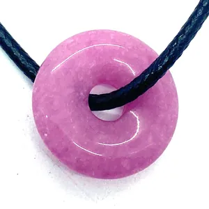 Macro detail of a purple donut pendant crafted from natural stone with a black cord