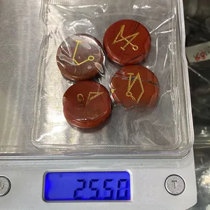 Dettaglio di quattro pietre energetiche in diaspro rosso con simboli dorati incisi