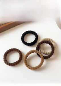 Close-up of elastic ribbed ponytail holders in neutral earth tones on white background