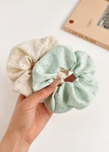 Detail of cream and mint green scrunchies with silver rivets and linen texture