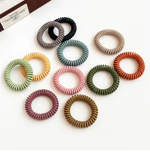 Macro detail of assorted matte Morandi color spiral phone cord hair ties on white