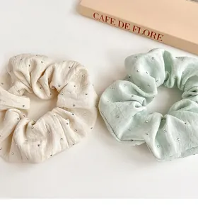 Close-up of cream and mint green fabric scrunchies with shiny rhinestone accents