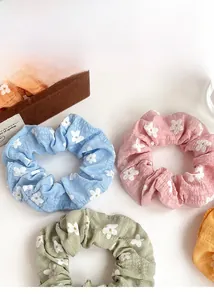 Detail shot of pastel floral scrunchies in pink, blue, and green on a wooden tray