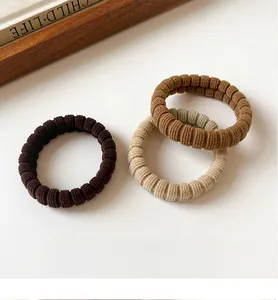 Close-up of three ribbed elastic hair ties in brown and beige earth tones texture