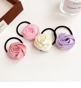 Macro view of 4-piece rose-shaped satin hair ties in pastel purple and cream colors