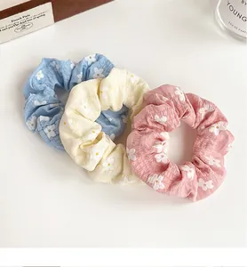 Three floral scrunchies in pink, yellow, and blue colors with soft pleated fabric texture