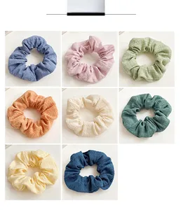Detail view of eight colorful textured scrunchies in a neat grid on white background