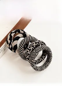 Macro detail of high-elasticity checkered hair ties in minimalist black and beige tones