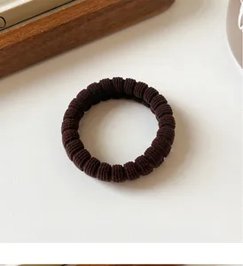 Detail of coffee-colored high elasticity ribbed hair tie on a minimalist background