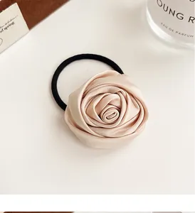 Detailed view of elegant champagne satin rose hair tie with high elasticity black band