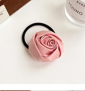 Detail of pink satin rose hair tie on black elastic band with luxury minimalist background