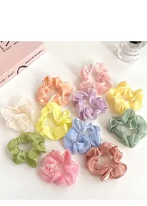 Chouchous en soie aux couleurs pastel macaron disposés sur un bureau blanc épuré