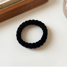 Macro view of black elastic hair tie featuring fine ribbed texture and seamless design