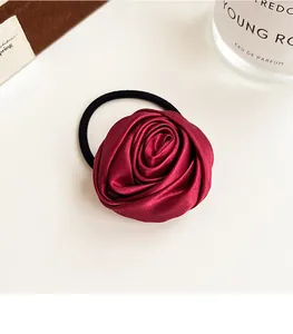 Detailed macro of a wine red satin rose hair tie with elastic band on white background
