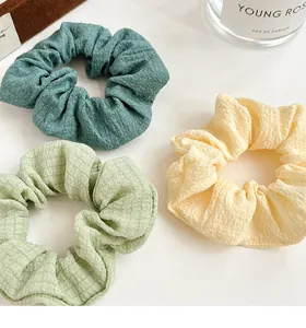 Detailed close-up of textured fabric scrunchies in green and cream yellow tones